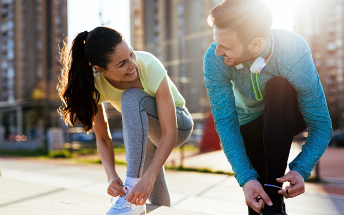 Energetic woman and man smiling and preparing for being active and working out in the city